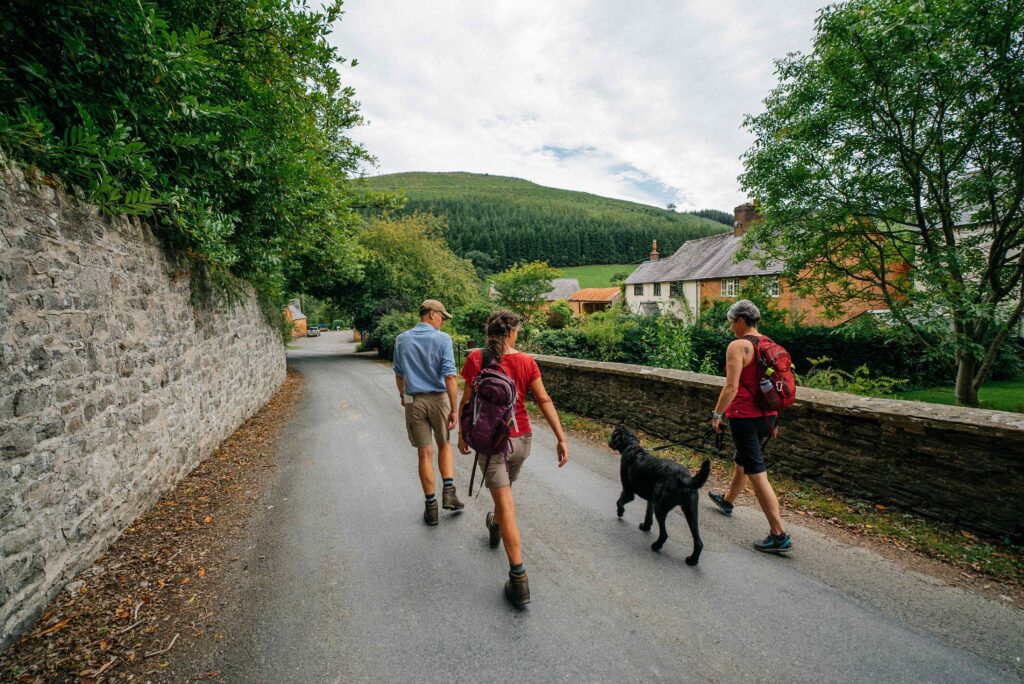 three people with a black dog, take a walk at Abbeycwmhir, on Glyndwr's Way.