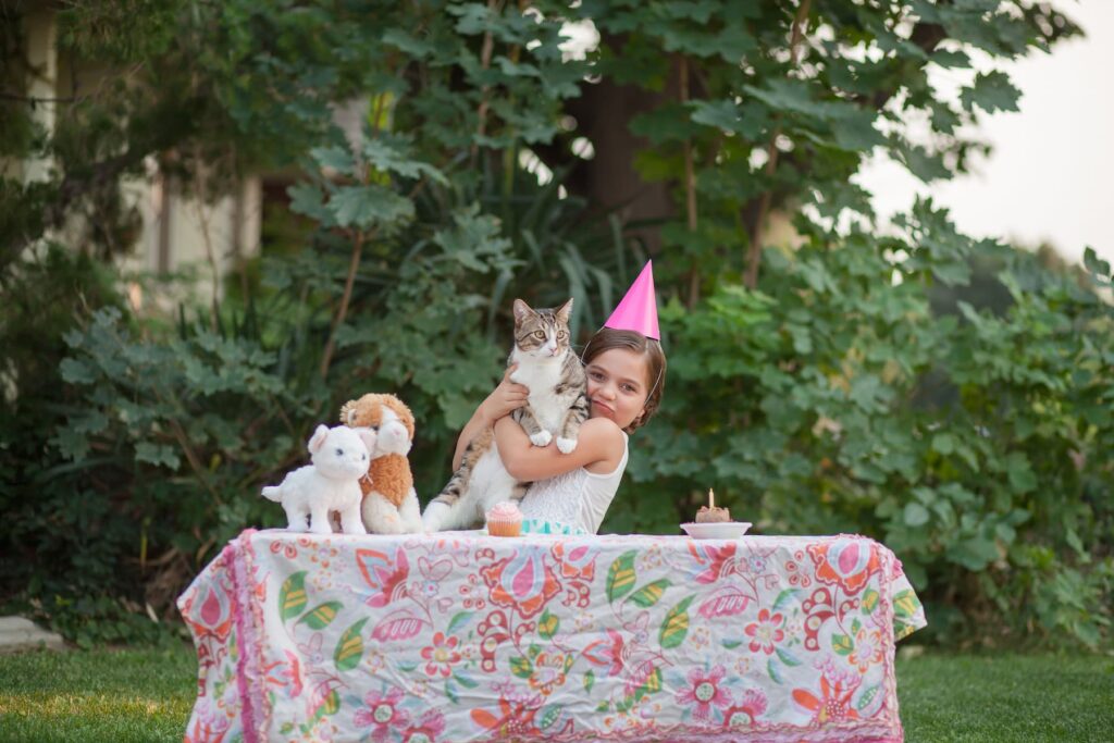 A Girl in a Birthday hat at a Party Hugging Her Pet Cat