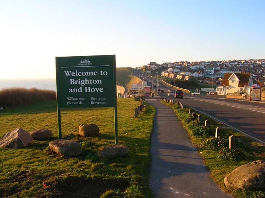 A road sign says ‘Welcome to Brighton and Hove’, with a road and houses in the background