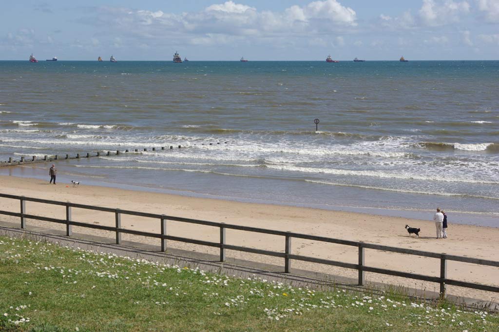 A wide shot of Aberdeen Beach, showing people walking their dogs on the sand