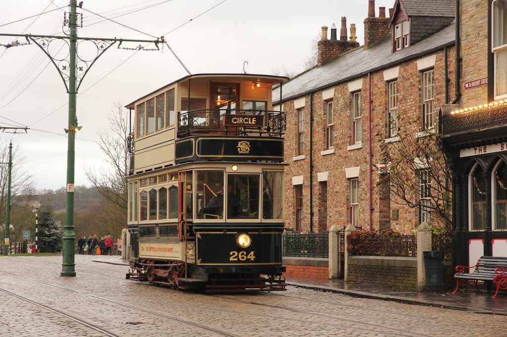 An old-fashioned tram at the Beamish Living Museum, with early 20th century brick buildings in the background