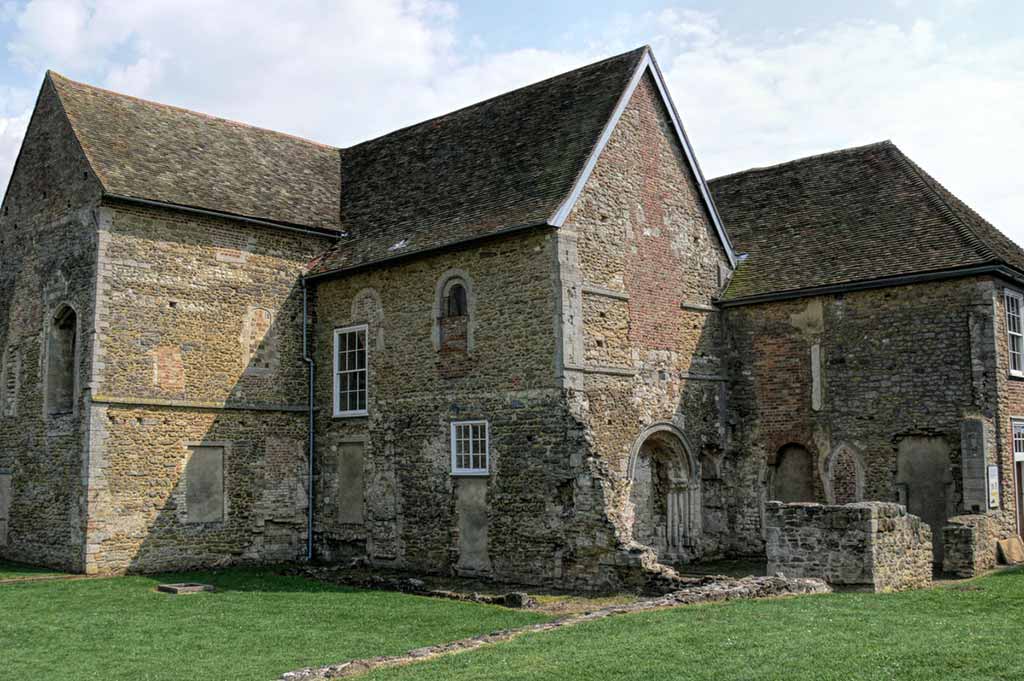 An old stone building called Denny Abbey stands in a green field in Cambridge