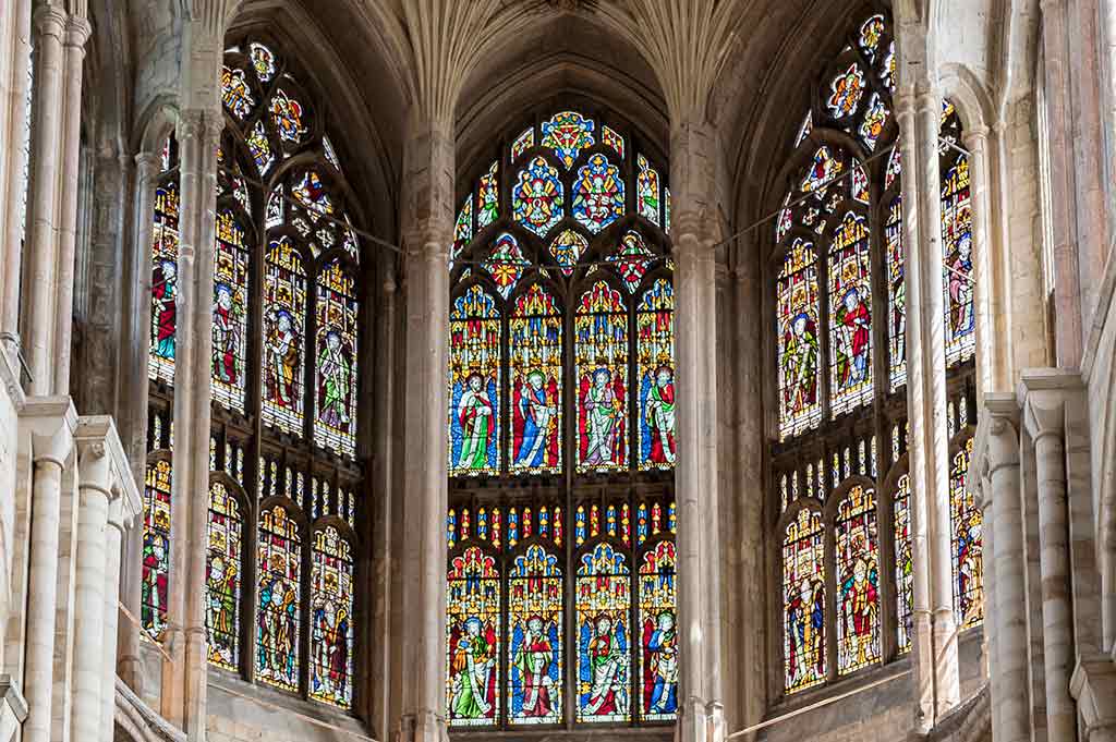 The interior of Norwich Cathedral, showing three ornate stained glass windows